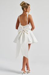 White dress with a large bow detail on the back, worn by a person on a plain background